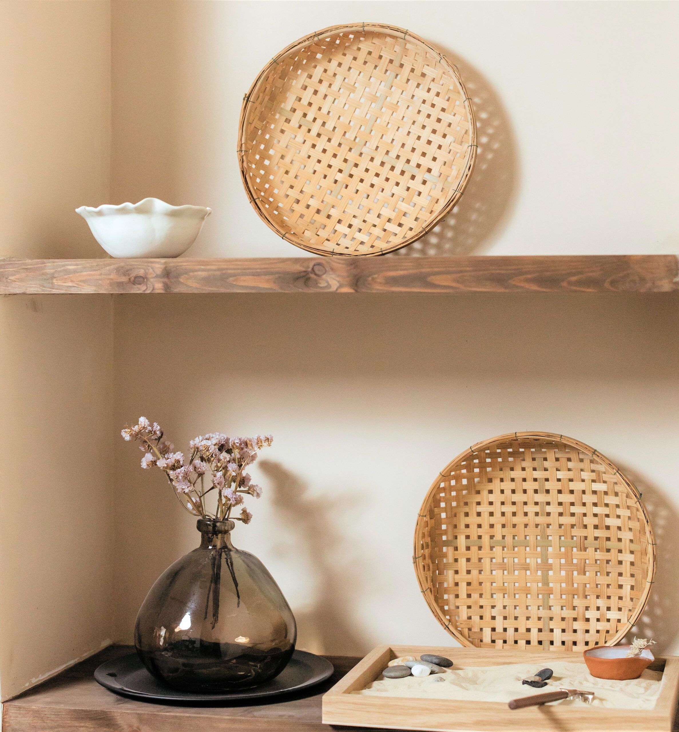 A set of three thick wooden shelves set on a white wall hold a variety of artisan made items.