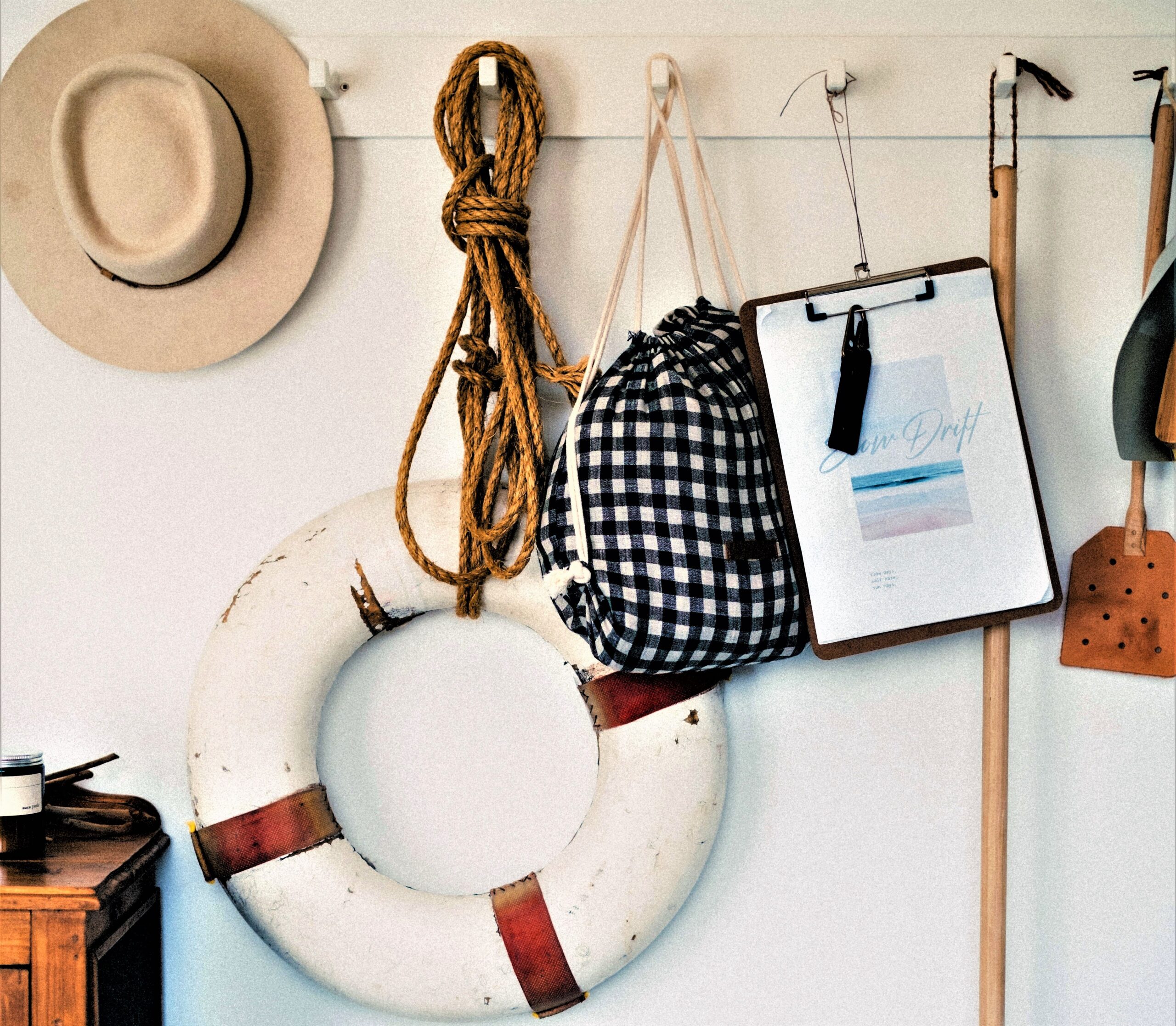 On a shiplap wall all painted in white, a series of hooks welcome various vintage accessories with a nautical theme.