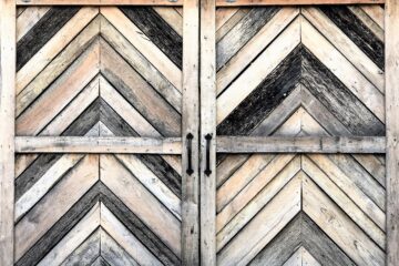 Rustic barn type sliding double closet door with oversize chevron pattern in grey-washed silvery planks.