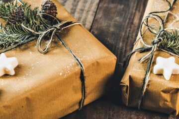 A couple of presents are wrapped in brown paper and adorned with twine and a few pine branches.