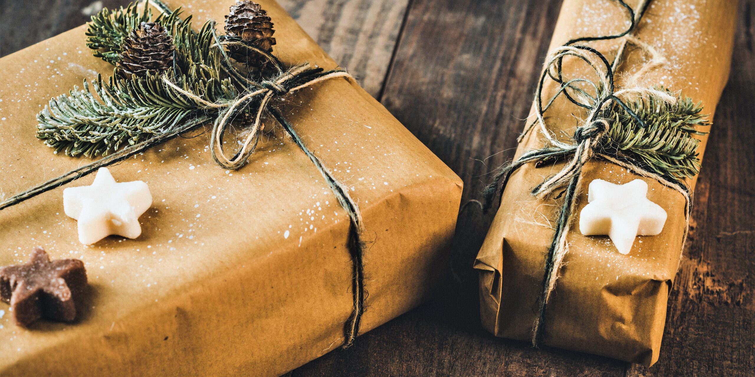 A couple of presents are wrapped in brown paper and adorned with twine and a few pine branches.