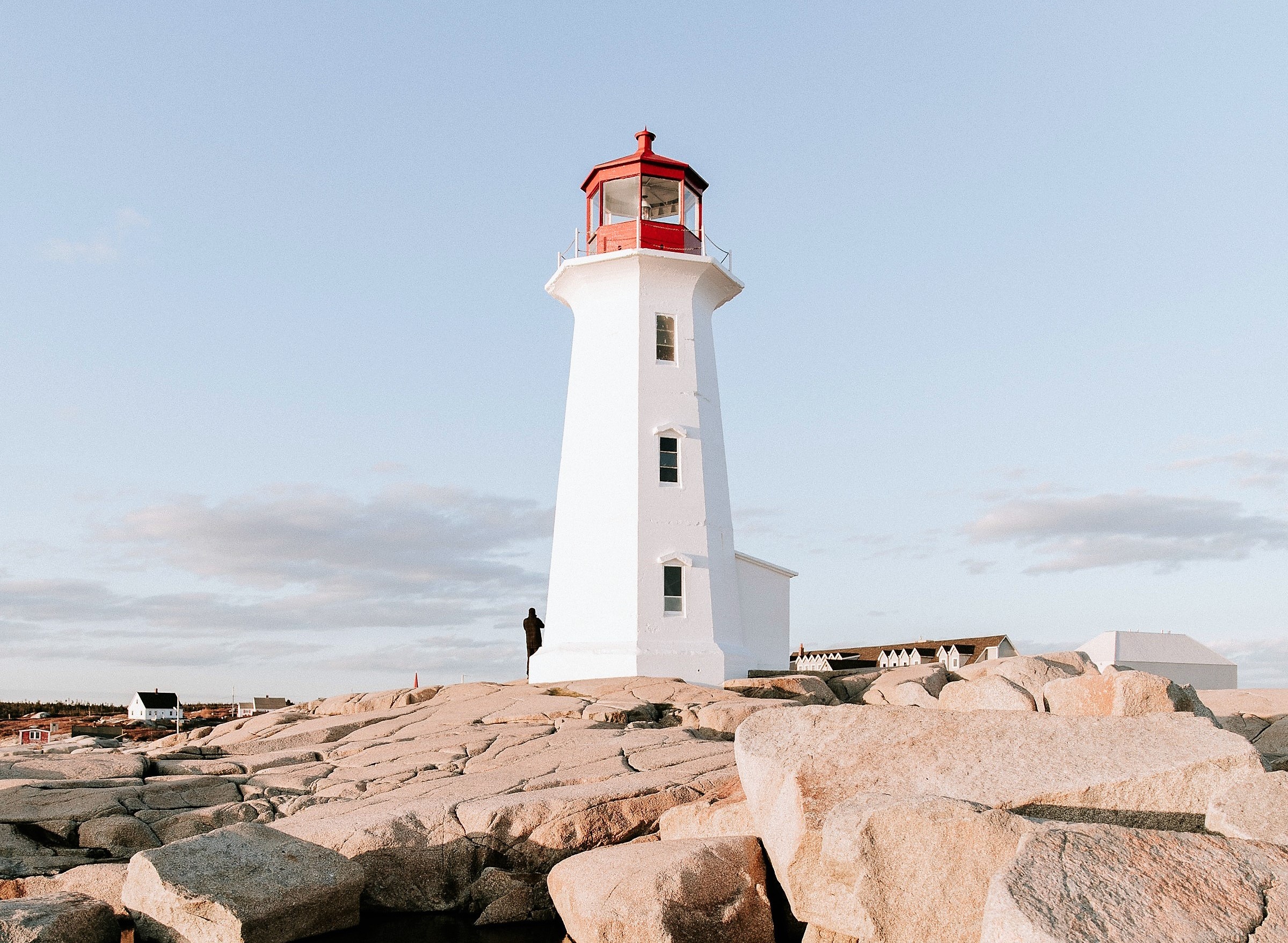 Peggy's Cove lighthouse stands tall in a clear blue sky on a bright and sunny day.